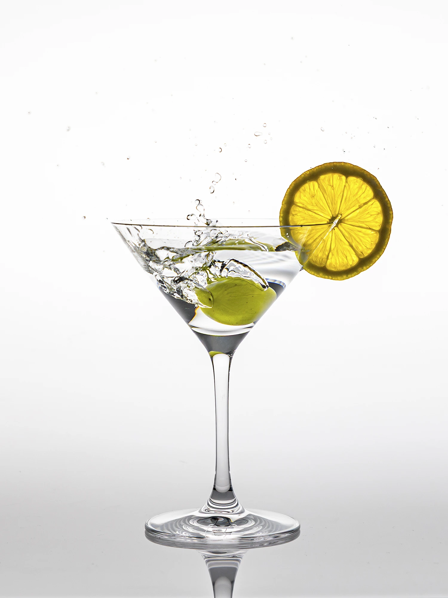 Ein Cocktailglas mit Gin , einer Olive und einer Limettenscheibe.